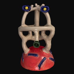 Face-like sculpture with a red base and small dark blue and yellow eyes