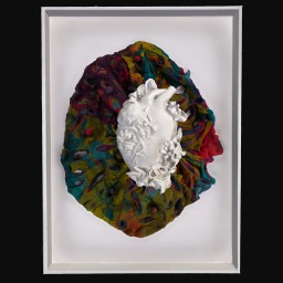 White coral heart sculpture against a multi-coloured cushion