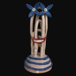 Face-like smiling sculpture with blue base and blue flower-shaped eyes